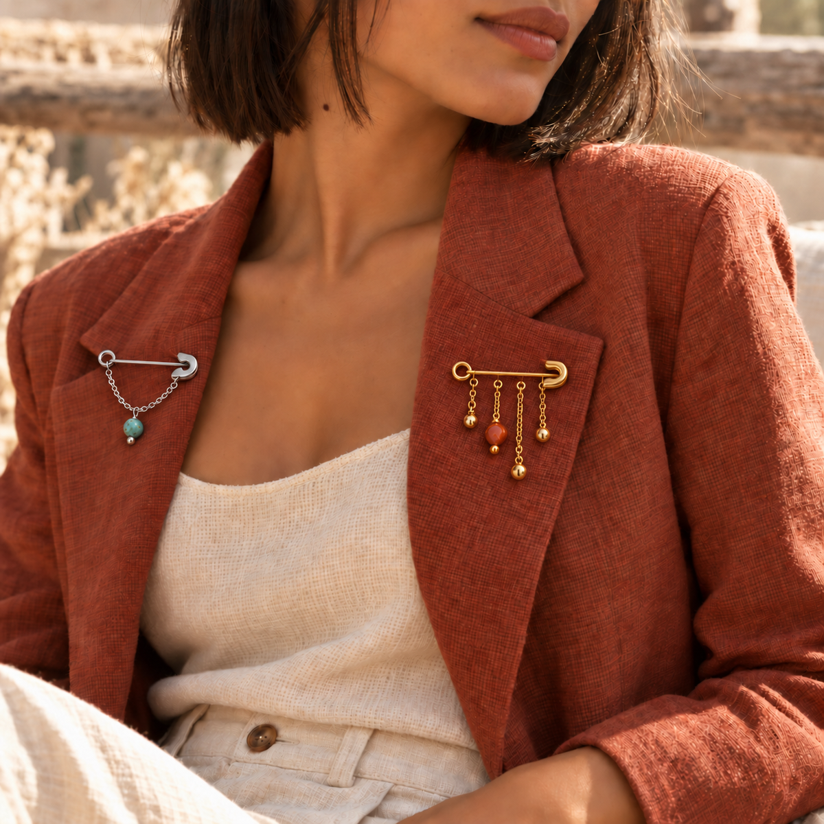 Broches dorée et argentée portées sur une veste terracotta — CARLI for M