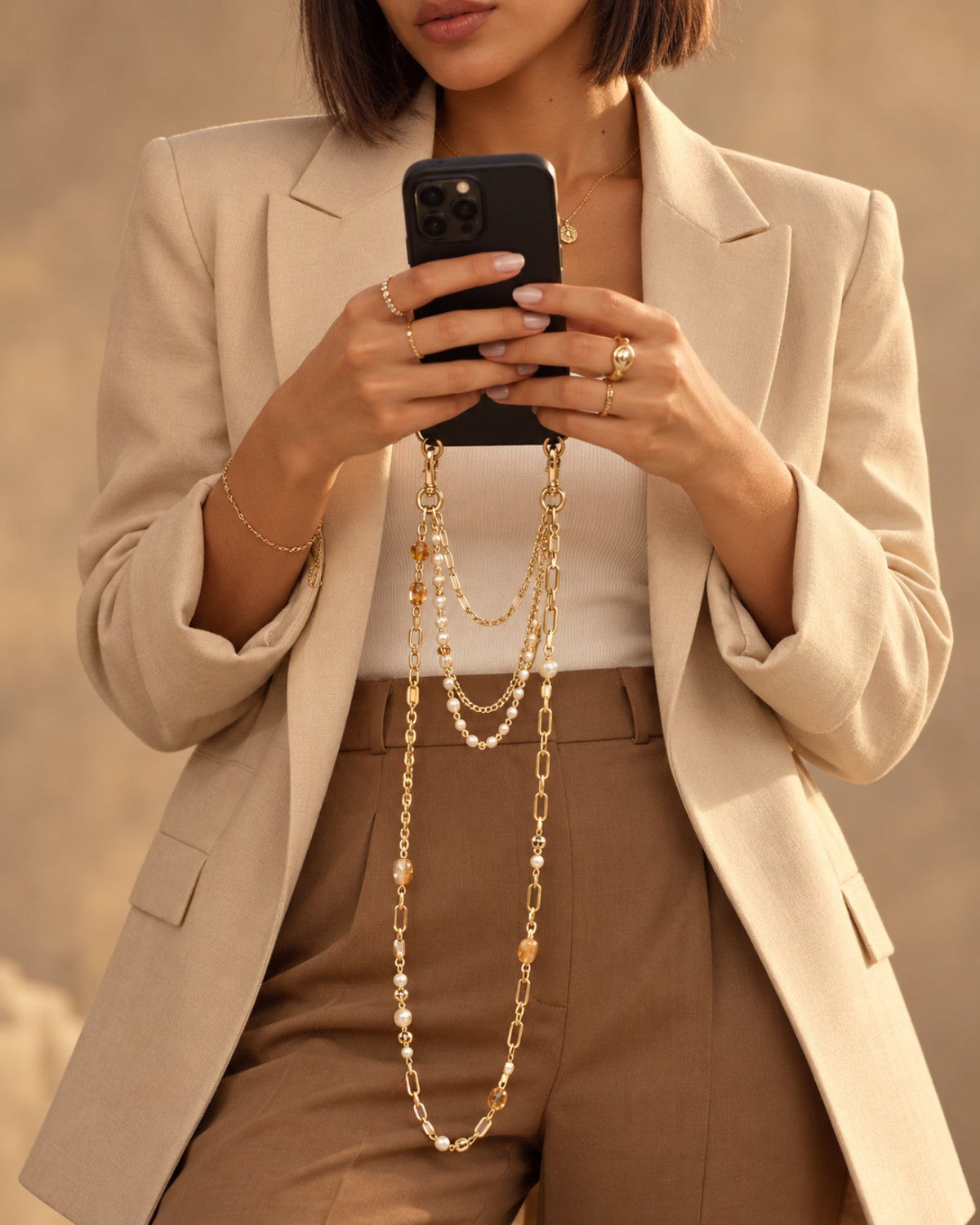 Bijoux de téléphone dorés et perles portés avec un ensemble beige — CARLI for M
